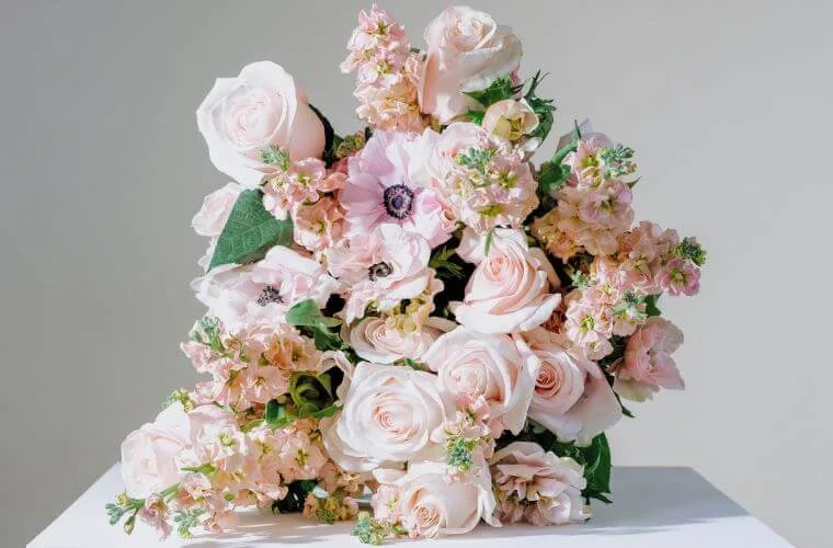 A pink and white bouquet of flowers including roses and anemones