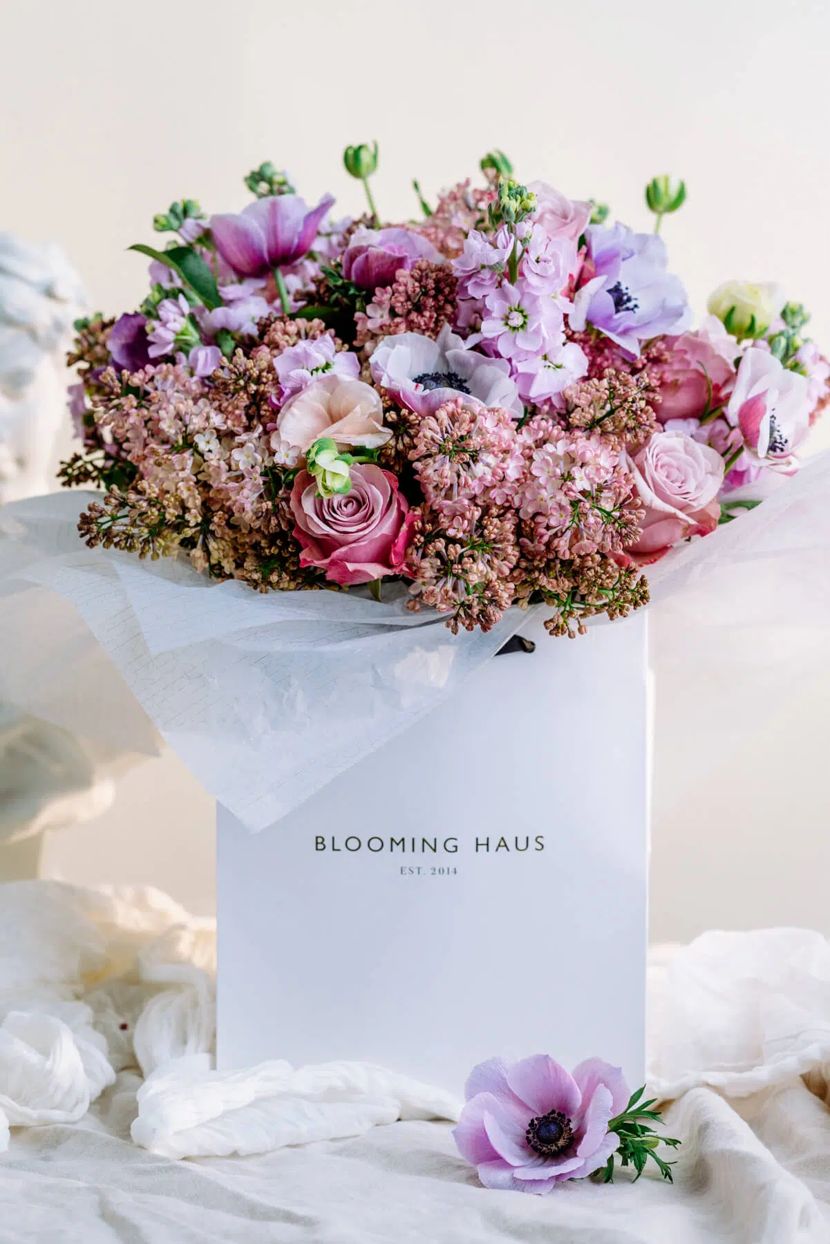 Anemone, purple roses, pink lilacs and purple stocks round bouquet by blooming haus