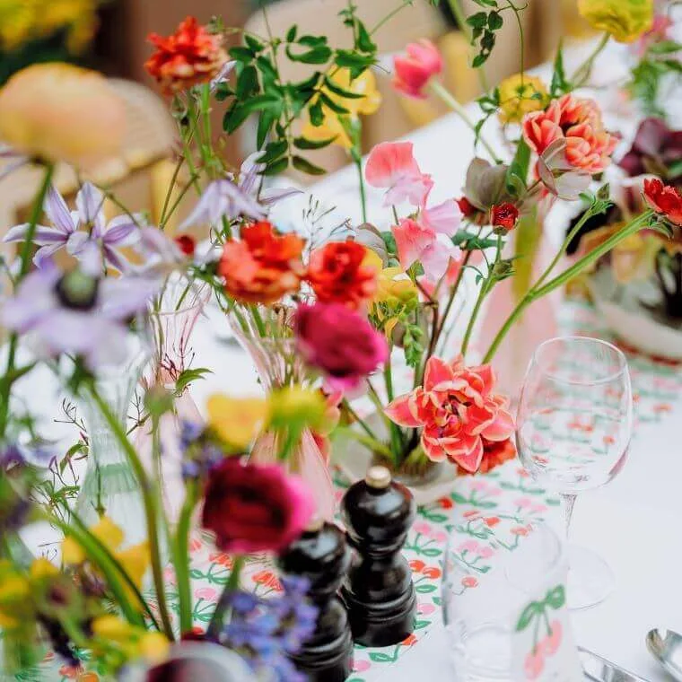 Table setting including condiments, a glass, and brightly coloured flowers