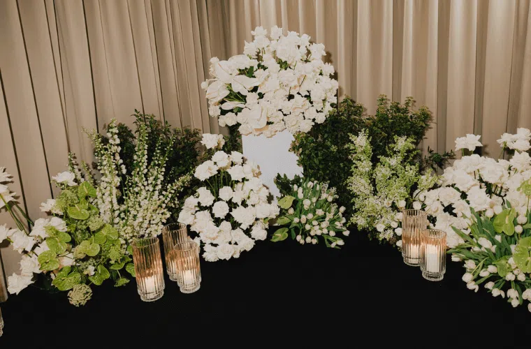White roses and lilies as part of a large floral display with green foliage