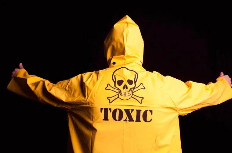 A person wearing a yellow coat with the word toxic and a skull and crossbones on it