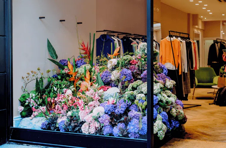 The window of me + em store with a large floral display in blue, pink, orange, and green