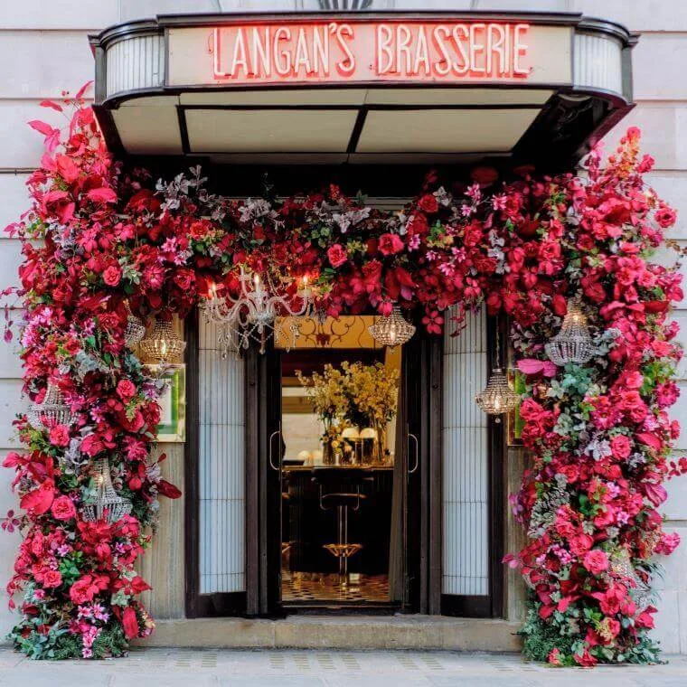 How can my business help fight climate change in 2025? 20 The entrance of langan's brasserie decorated with dark pink flowers from blooming haus