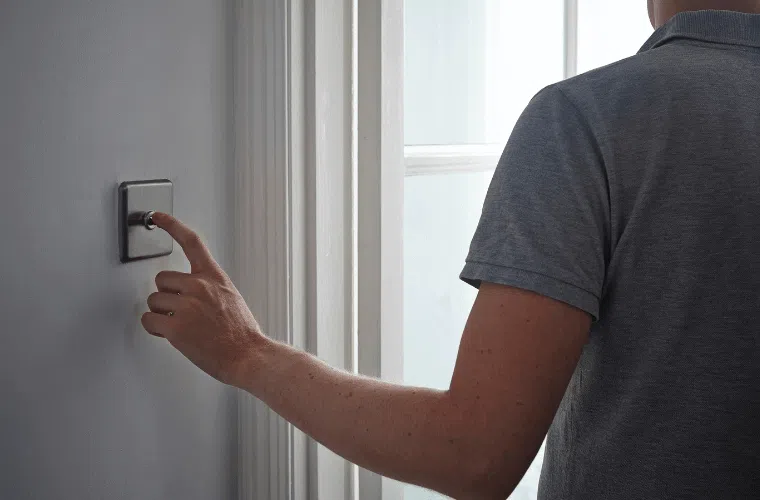 How can my business help fight climate change in 2025? 12 A man with his back to the camera switching off a light switch