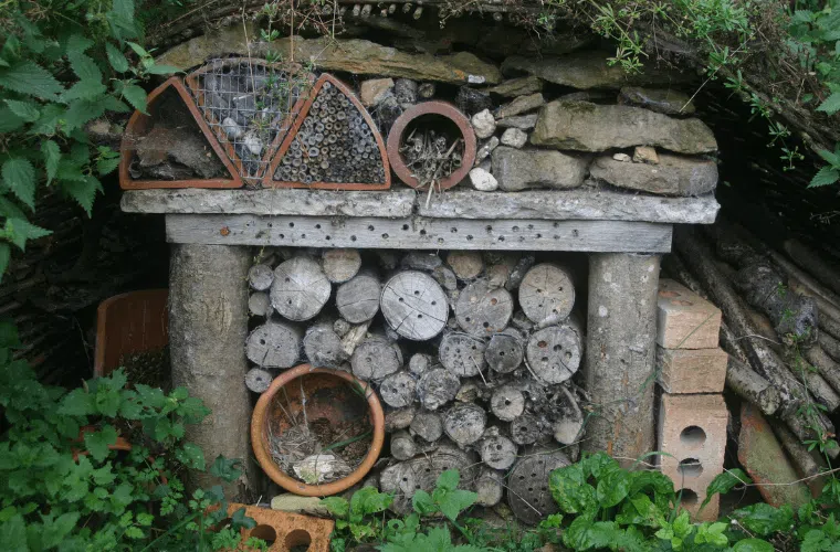 A bug hotel made from natural materials in a garden setting