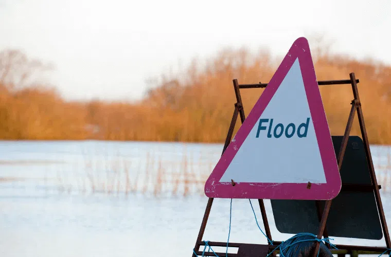 A flood warning sign with a flooded field