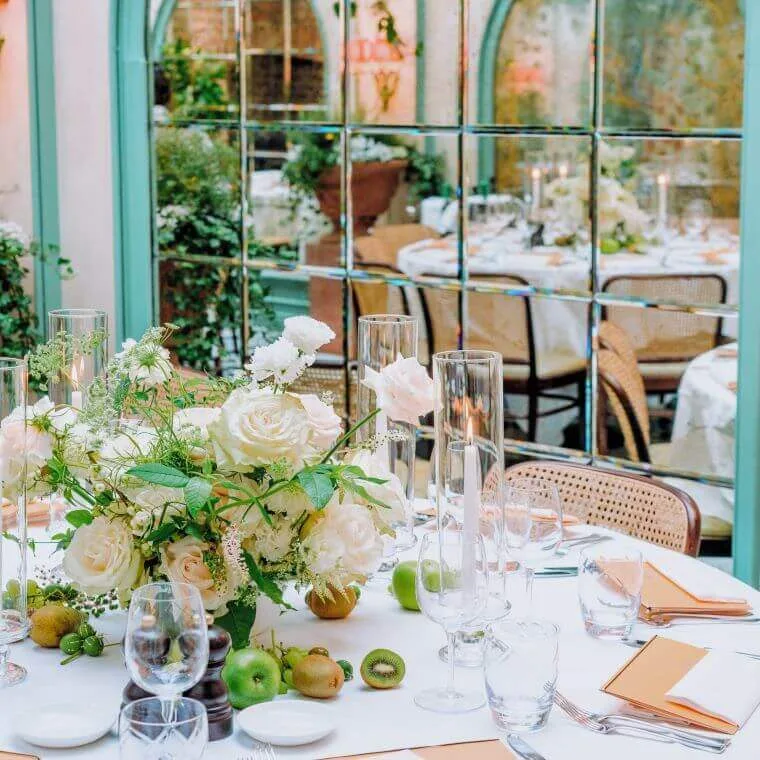Weddings at daphne's london | our honest review 2025 2 A table set with a floral centrepiece at daphne's with its refection in the window