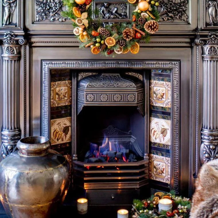 A fireplace decorated with wreaths on the mantelpiece and hearth
