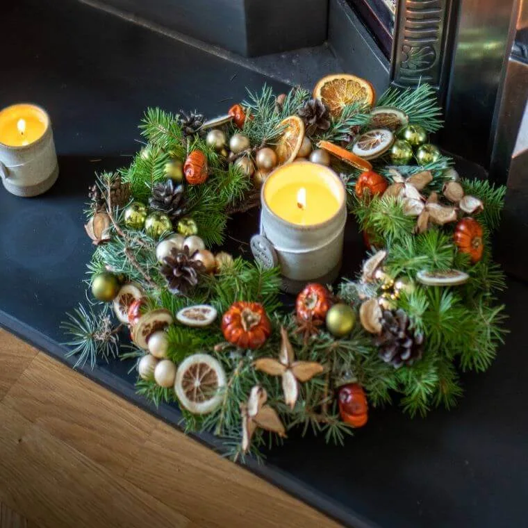 An autumn wreath on a ledge with candles placed beside it