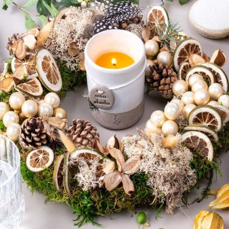 A finished wreath with pine cones and dried fruit with a candle in the centre