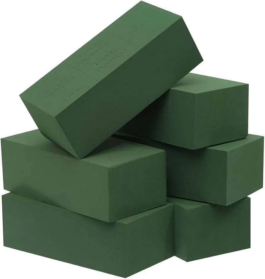 A stack of six dark green floral foam blocks arranged unevenly
