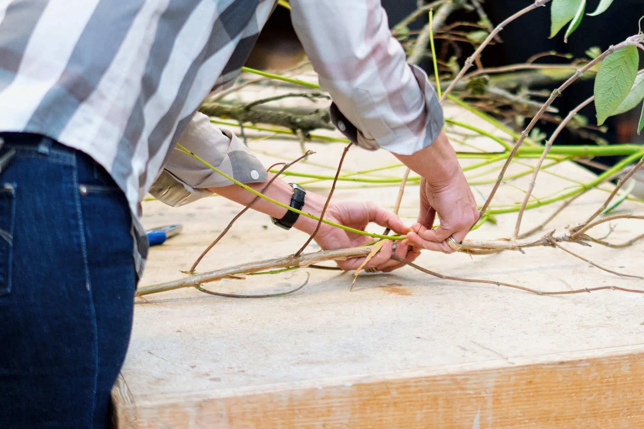 Florist creating a sustainable bridal bouquet using a natural branch base instead of floral foam